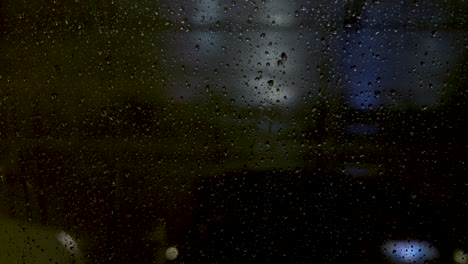 cars passing in front of a window full of raindrop at night