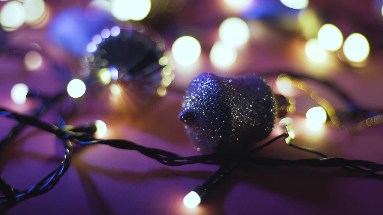 Close-up shot of garland with golden lights and christmas toys on color background. Christmas concept. Home decor. Beautiful bokeh