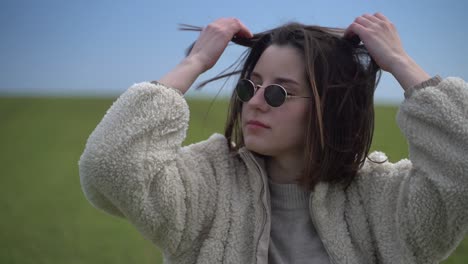 a young beautiful brunette girl walks through a green meadow. she looks directly inyo the camera. portrait.