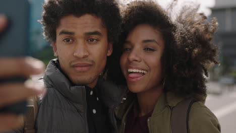 Retrato-De-Una-Joven-Pareja-Afroamericana-Posando-Tomando-Fotos-Usando-Un-Teléfono-Inteligente-Disfrutando-De-Viajar-Juntos-Fondo-Urbano