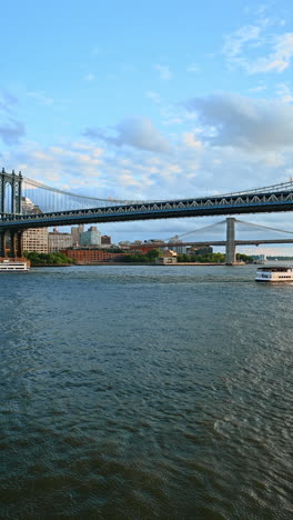 Riverboats go under the Manhattan Bridge. The Brooklyn Bridge can be seen at backdrop. View from waterscape. Vertical video