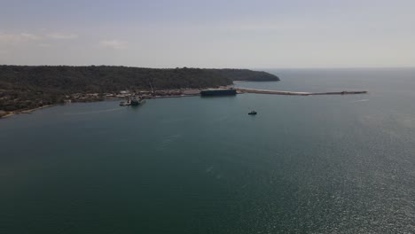 Aerial-drone-view-of-Port-Caldera-facility-with-container-ship-parked-in-the-dock-discharging-cargo,-Puntarenas,-Costa-Rica