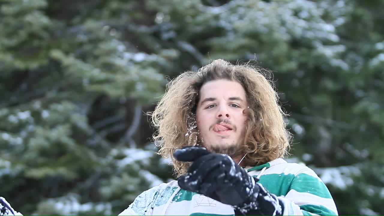 스키 슬로프에서 한 청년이 머리에서 눈을 털어내기 위해 휴식을 취하고 있다