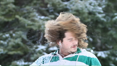 a young man on a ski slope takes a break to shake the snow out of his hair