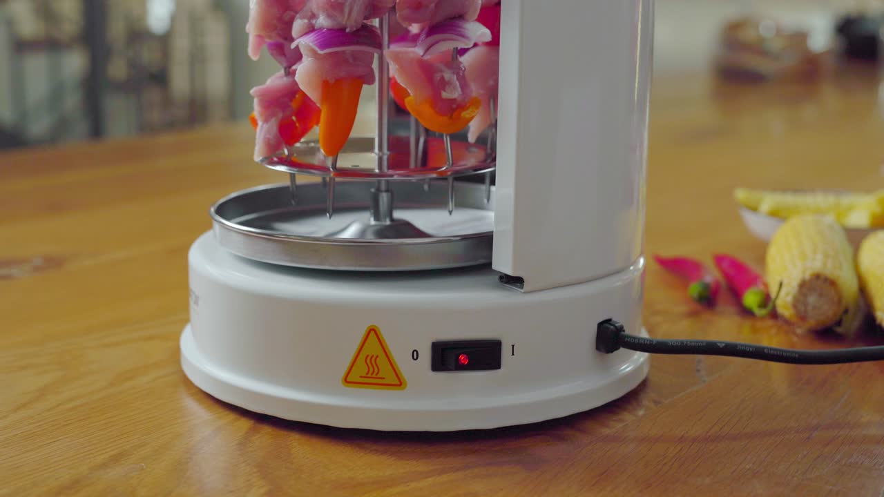 Female hand clicking on button for electric Shish kabob grill with skewers