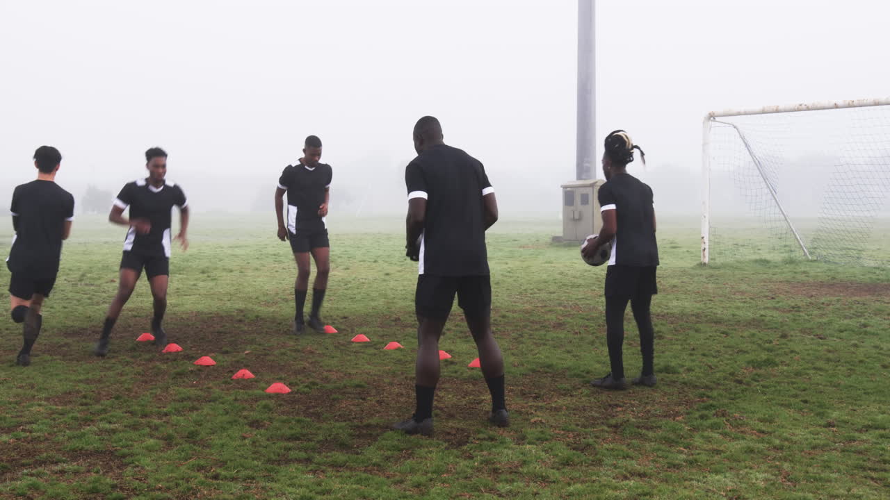 Soccer players practicing drills on foggy field, focusing on teamwork and skills