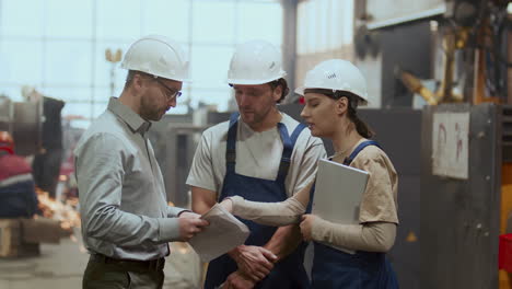 industrial engineer discussing work plan with two factory workers