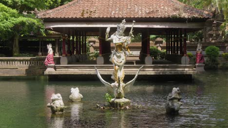 a pond at pura gunung kawi sebatu temple in bali, indonesia, featuring an intricately carved statue surrounded by smaller sculptures