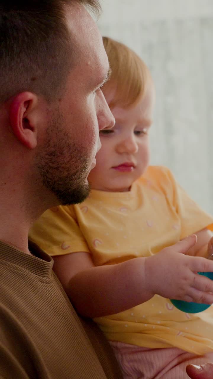 Tender Moments: A Father and Child Share a Sweet Connection While Engaging with a Colorful Toy in a Warm, Cozy Setting, Capturing the Essence of Family Bonds and Childhood Wonder