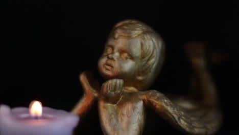 angel figurine looking at the candle in the dark