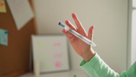 little girl learns to spin pen in fingers in class at break