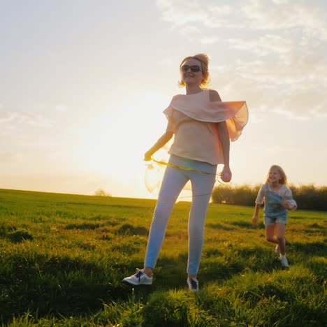 carefree young woman with balloons walking on a green meadow at sunset 2