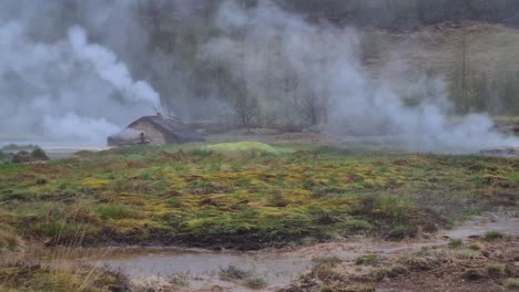 geothermal area in landscape of iceland, vapor moving above land on rainy day