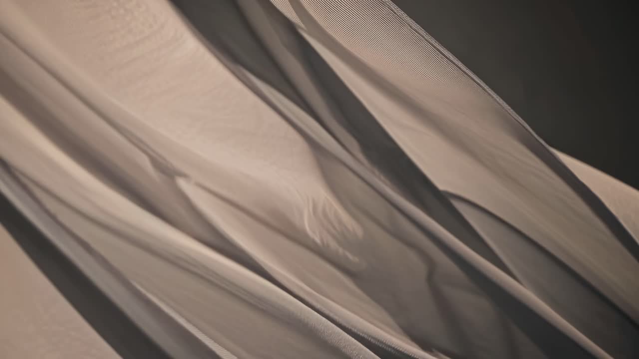 Close-up video of flowing fabric with soft lighting, creating a serene and abstract visual
