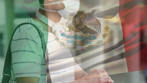 animation of flag of mexico waving over latin man wearing face mask in city street