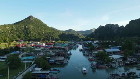 Luftaufnahmen-In-Richtung-Des-Fischerdorfes,-Die-Ein-Sich-Bewegendes-Boot,-Festgemachte-Boote,-Eine-Schöne-Landschaft-Zeigen