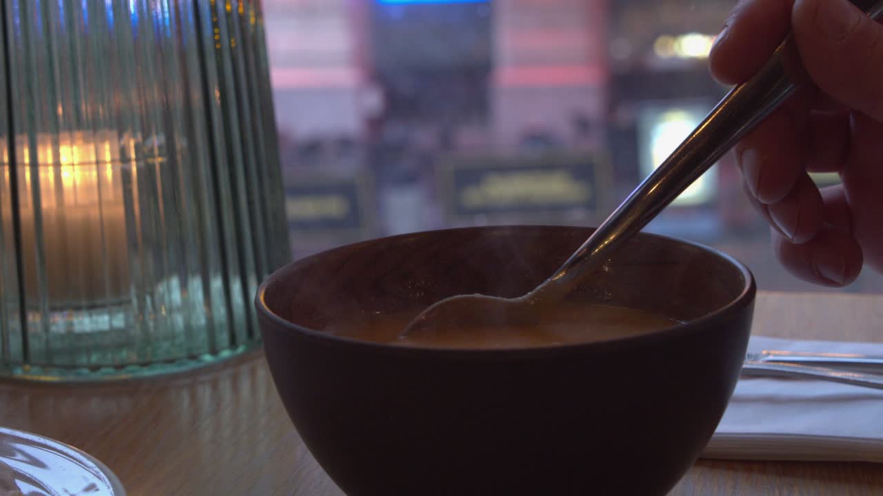 sopa abundante y humeante de cerca en el café, frío invernal fuera de la ventana