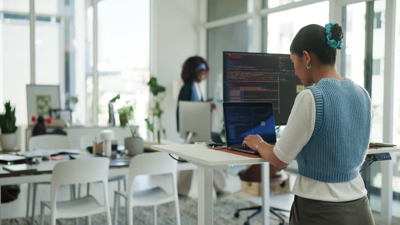 Woman Coding on Laptop at Standing Desk in Modern Office