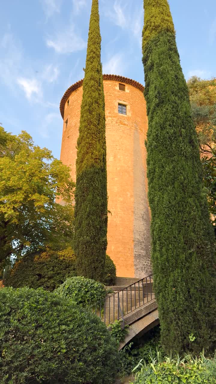 Medieval tower amidst lush gardens in Girona, calm panning outdoor view