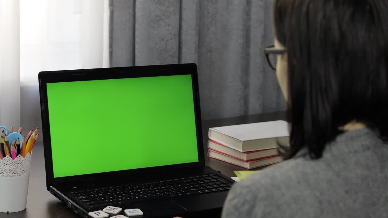maestra haciendo llamada de video de educación a distancia en línea en la pantalla verde de la computadora portátil