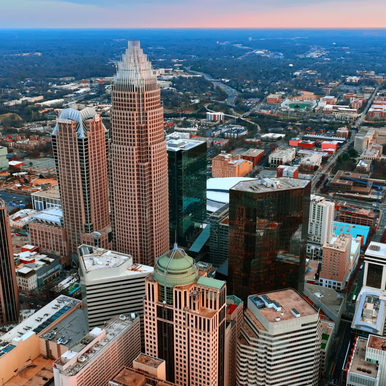 Vackra skyskrapor i den övre delen av den amerikanska staden Charlotte, NC. Vidsträckt stadsmiljö med mycket grönska i bakgrunden.