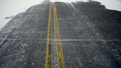 snow blows across and empty road on a cold winter day.