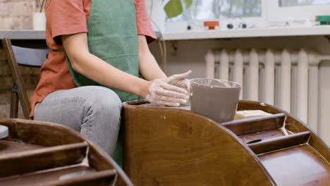 manos de un empleado que modela una pieza de cerámica en una rueda de alfarero en un taller 1