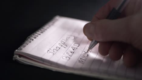 hand writing shopping list on notepad for essentials close up shot