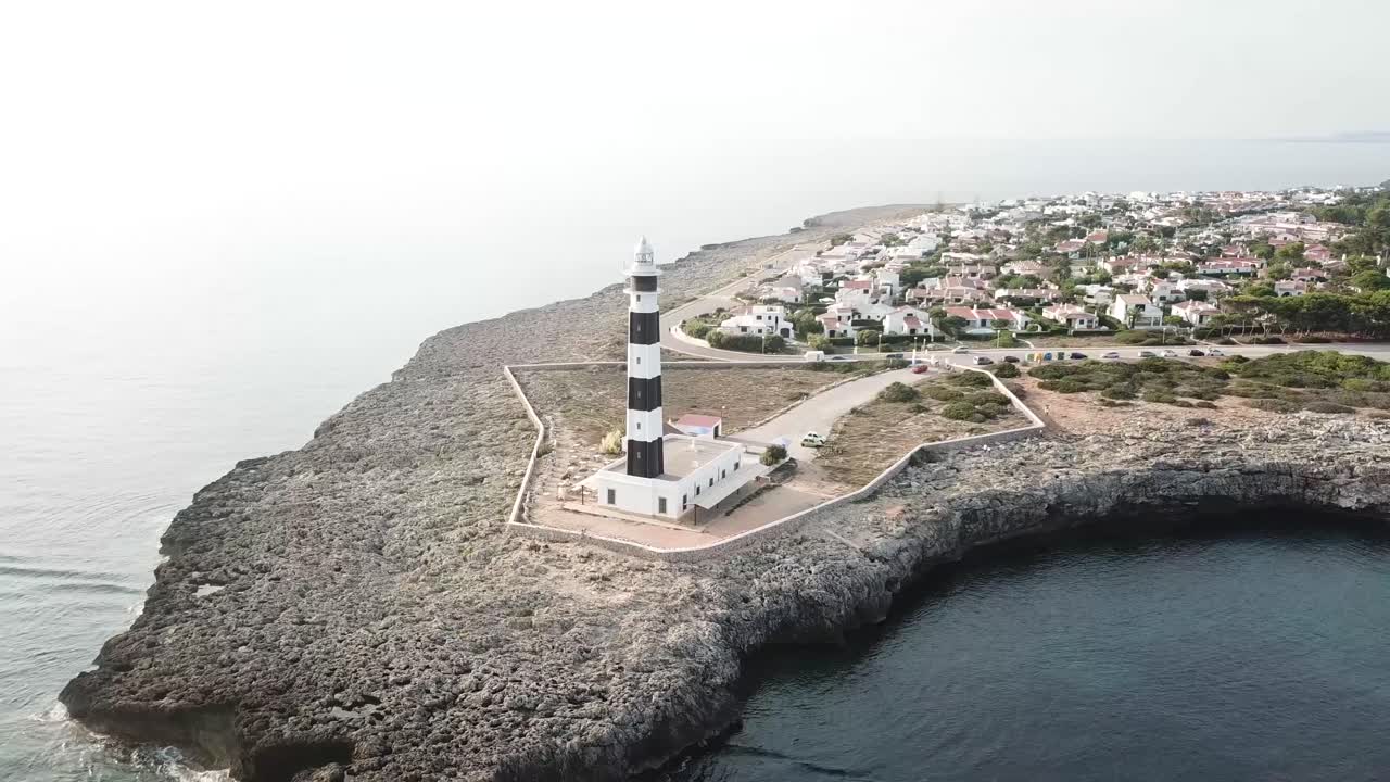 스페인 메노르카 섬에 있는 캡 다르트루트 등대의 공중 전망 - 드론 궤도