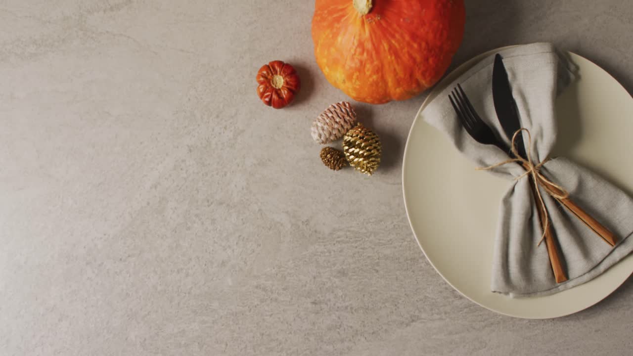 video de cubiertos, plato y decoración de otoño con calabaza acostada en superficie gris