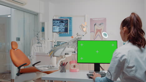 Woman-working-as-dentist-with-green-screen-on-monitor