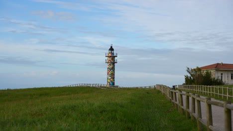 colorful lighthouse in ajo, cantabria with vibrant geometric art by okuda san miguel on a windy day