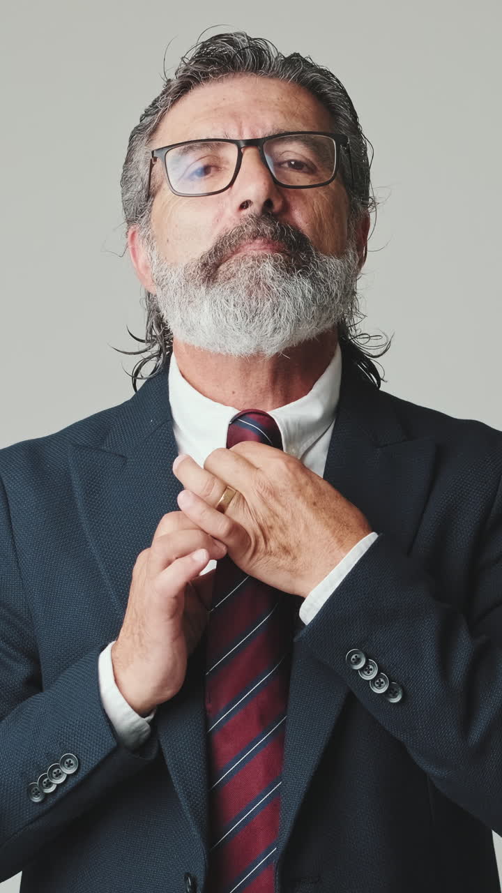 Uomo d'affari maturo si sistema la cravatta in uno studio