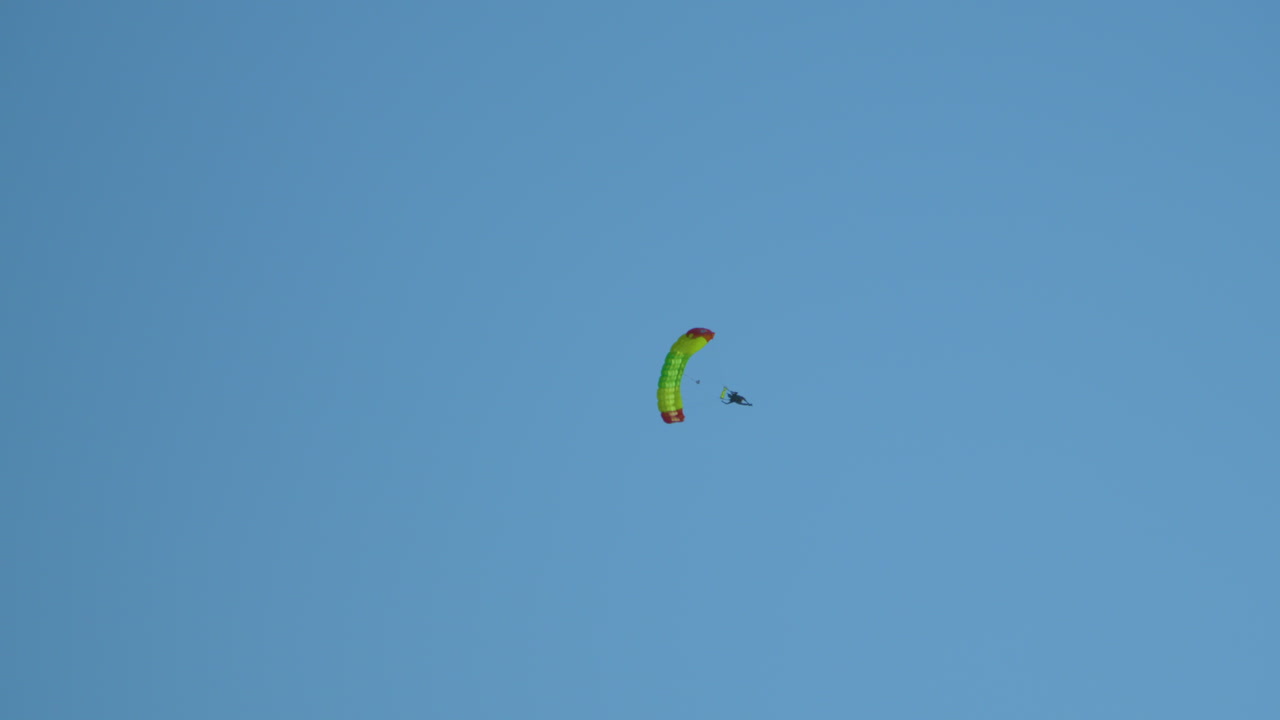 paracaidista volando con un paracaídas en un cielo despejado azul