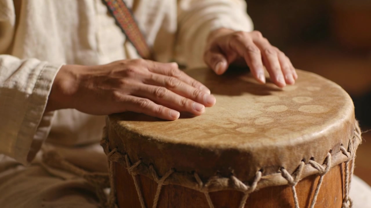 Hands lifting, player performing palm finger taps on drumhead in studio making rhythm with strap