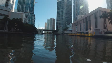 Vista-Desde-Un-Pequeño-Bote-Mientras-Viaja-A-Lo-Largo-De-Los-Tranquilos-Canales-De-Miami,-Florida,-Con-Edificios-Altos-Que-Bordean-La-Costa.