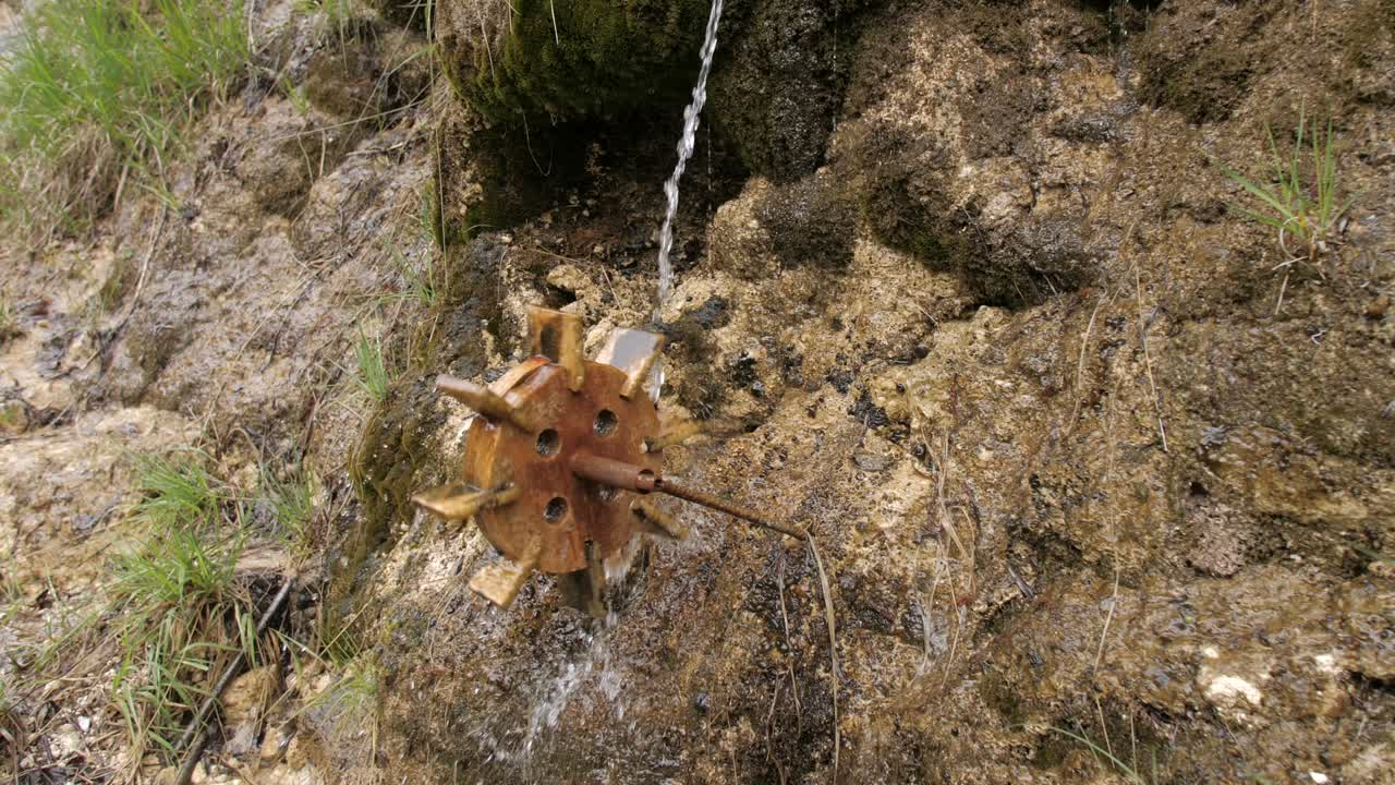 pequeño molino de agua de juguete de madera girando mientras el agua cae, zoom en cámara lenta
