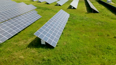 Close-up-aerial-shot-over-renewable-energy-solar-farm-panels-in-lush-green-field