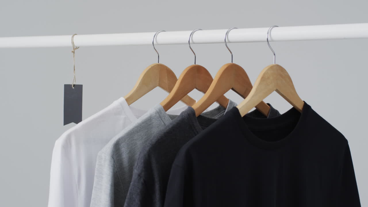 Video of four t shirts on hangers and copy space on white background