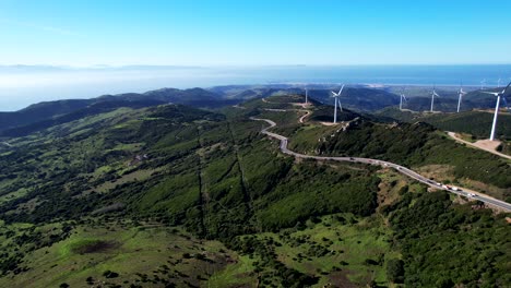 Aerial-pan-across-wind-turbine-energy-generator-above-lush-green-valley-in-spain