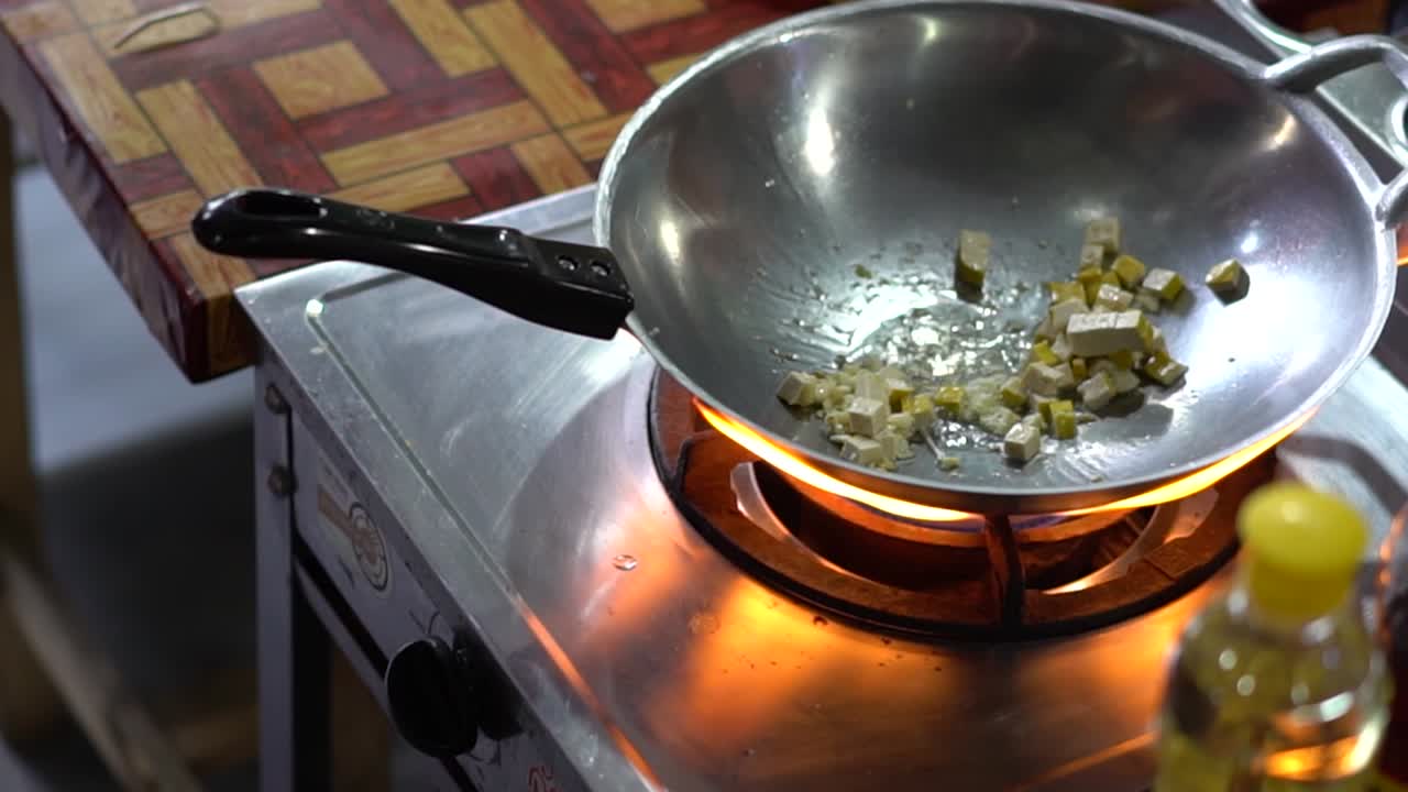 Person Cooking Tofu with a Wok, Turning Up the Heat on the Stove to Cook Pad Thai in an Outdoor Kitchen in Bangkok Thailand SLOW MOTION