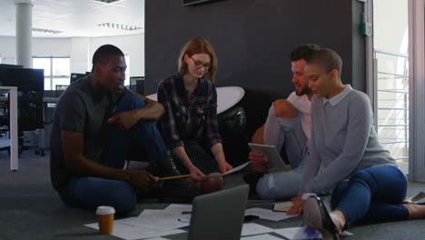 front view of young cool mixed-race business team planning and sitting on floor of modern office 4k