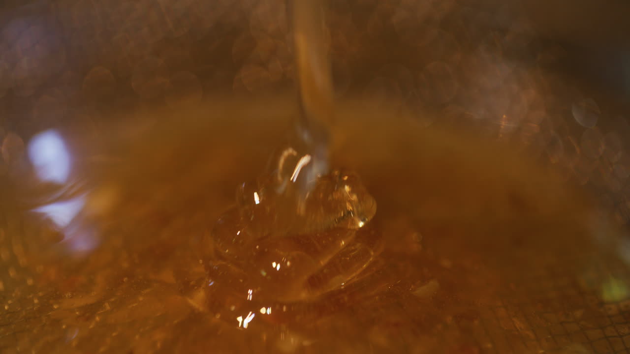 Cono di miele dorato che cola attraverso un setaccio