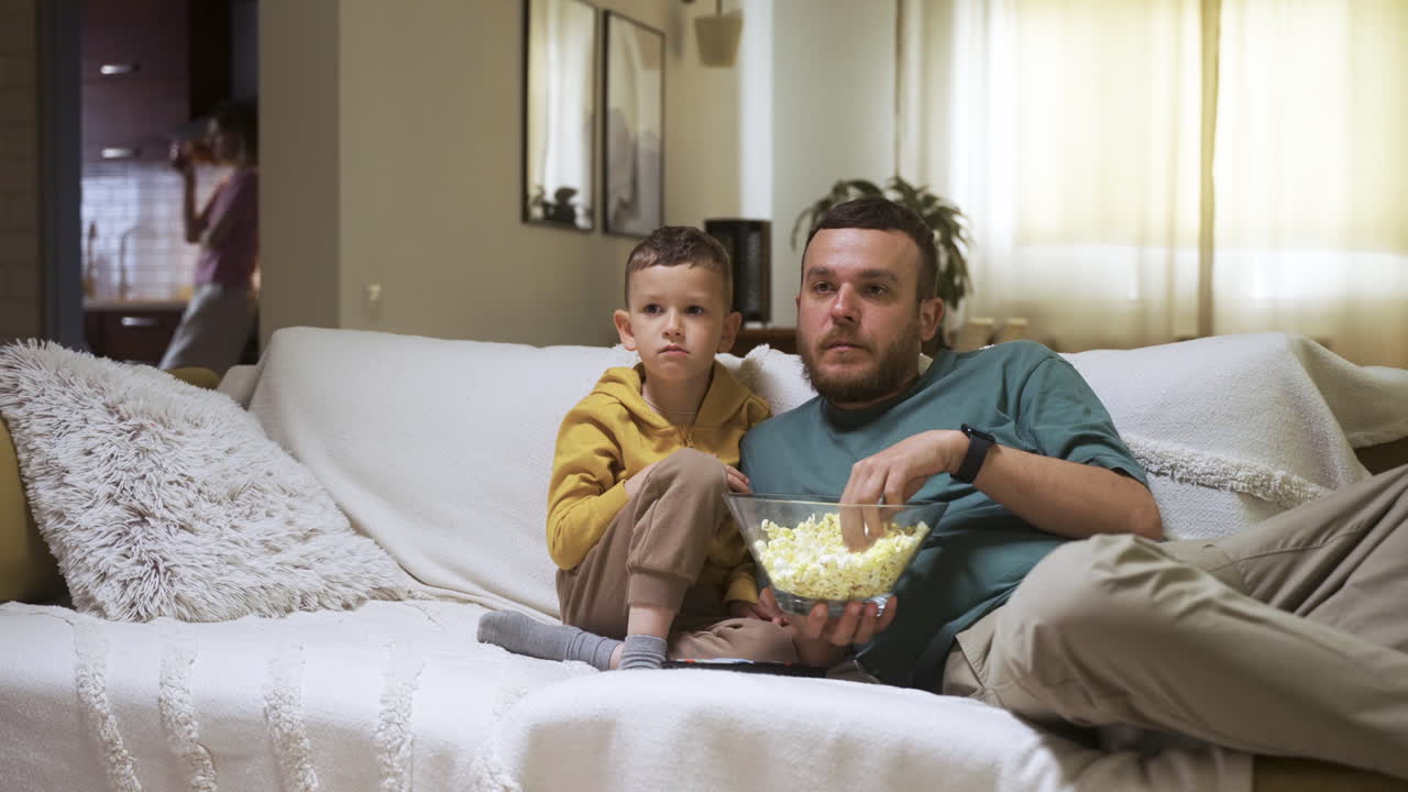 Famiglia seduta sul divano che guarda un film.