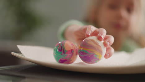 child puts easter egg with ebru design onto plate at home