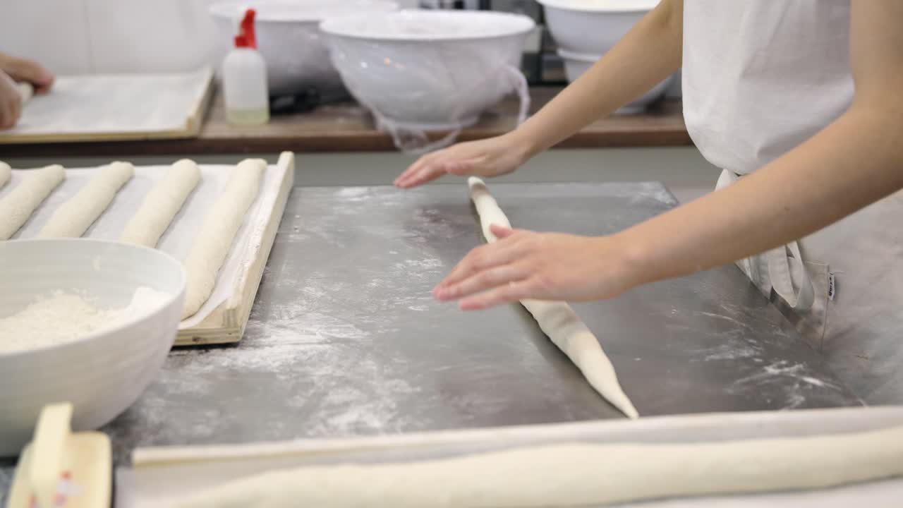 Baker's Hands Shaping Fresh Baguette Dough on a Floured Surface