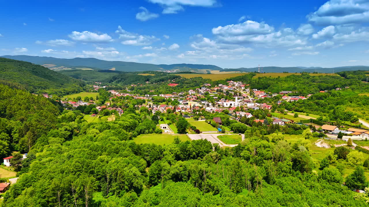 Approaching a beautiful village located in the picturesque nature. Fantastic countryside under the blue sky. Slovakia from aerial view.