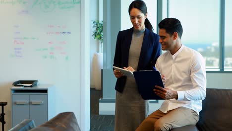 Business-colleagues-discussing-over-digital-tablet-and-clipboard