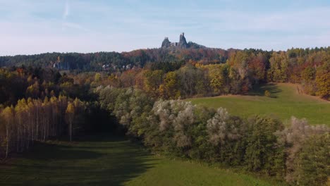 flying-above-a-meadow-and-a-forest-towards-czech-castle-ruins-Trosky