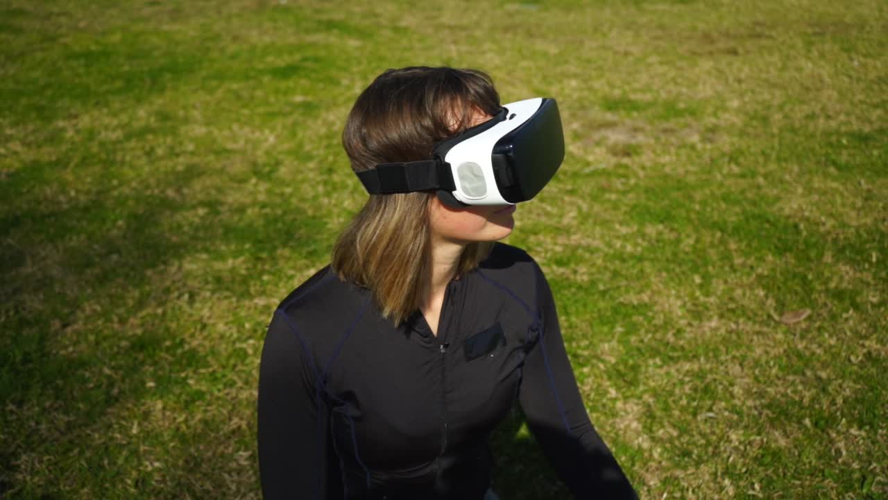 mujer joven en ropa deportiva usando auriculares de realidad virtual en el parque